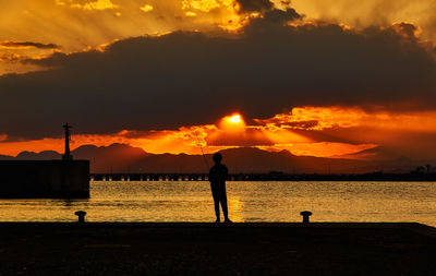 Silhouette people standing on beach against sky during sunset