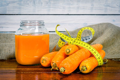 Carrot by juice and yellow measure tape on table