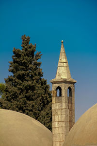 Charming historic minaret stands proudly before a vibrant blue sky, symbolizing cultural heritage. 