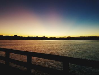 Silhouette plants in front of calm sea at sunset