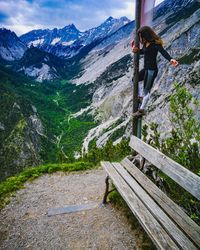 Full length of young woman standing on pole against mountain range