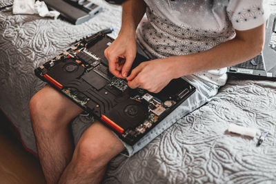A young man is changing the thermal paste on a laptop.