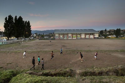 High angle view of people playing soccer on land against sky at sunset