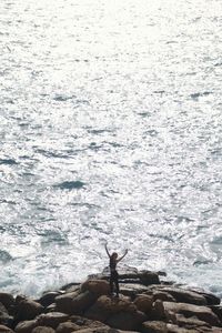 Man standing on rock by sea