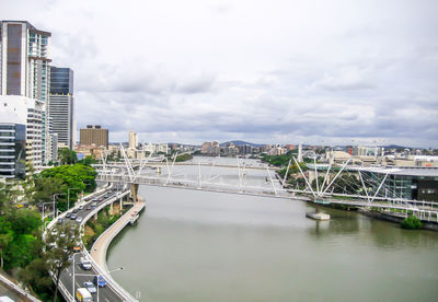 Bridge over river in city against sky