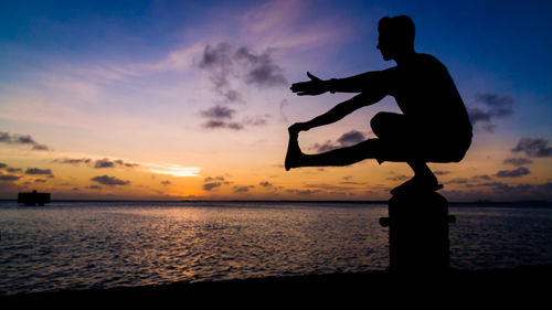 Silhouette man on beach against sky during sunset