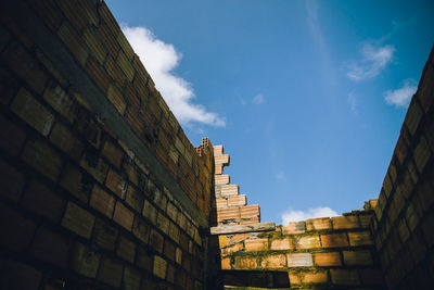 Low angle view of brick wall against blue sky