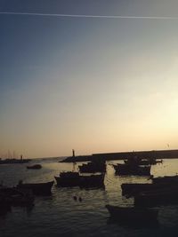 Boats moored on sea against sky during sunset