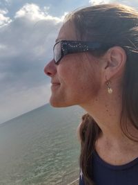 Portrait of woman with sunglasses at beach against sky