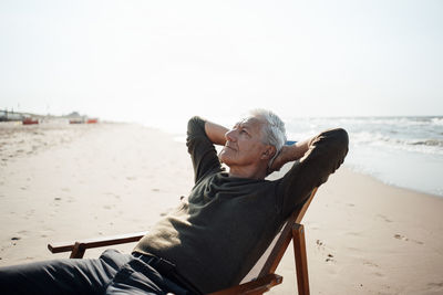 Side view of woman sitting on beach