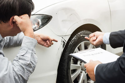 Insurance agent pointing at broken car to customer