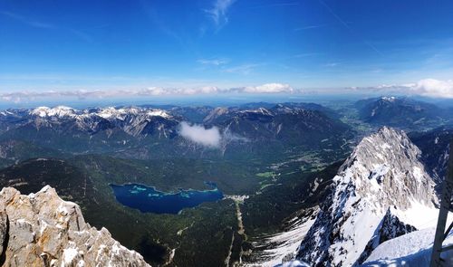 Aerial view of snowcapped mountains against blue sky