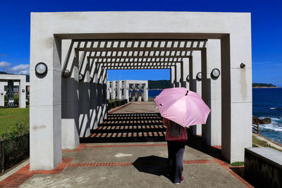 Rear view of woman with umbrella standing outdoors