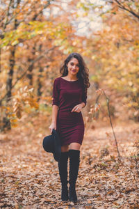 Full length portrait of young woman during autumn