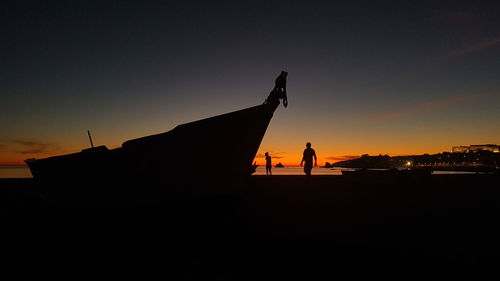 Silhouette people standing on land against sky during sunset