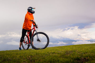 Low section of man riding bicycle on field against sky
