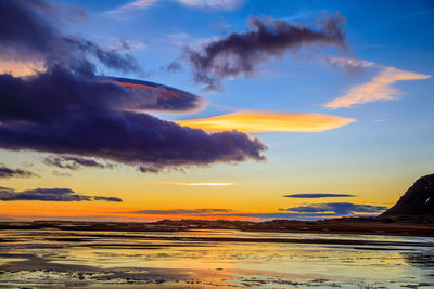 Scenic view of sea against dramatic sky during sunset
