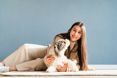 Beautiful brunette woman with playful mixed breed dog, embracing and having fun at home