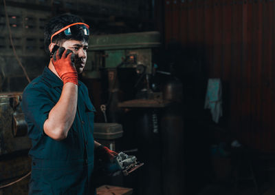 Man talking on mobile phone while working in factory