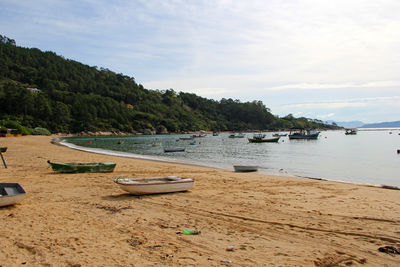 Boats moored on beach against sky