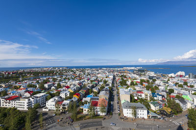 High angle view of townscape by sea against blue sky