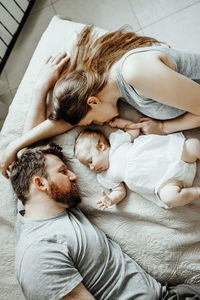 Baby sleeps with daddy and mom on the bed, happy family at home