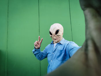 Cropped hand of man with arms crossed against wall