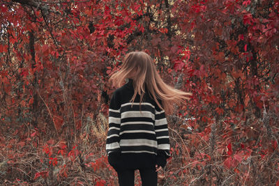 Rear view of woman standing in forest during autumn