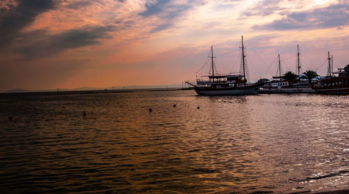 Silhouette sailboat in sea against sky during sunset