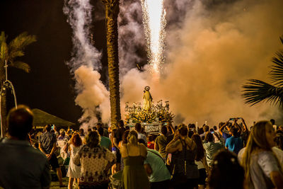 Panoramic view of crowd at park against sky at night