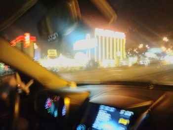 Illuminated city seen through car windshield at night