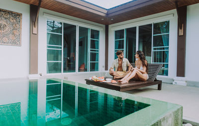 People sitting in swimming pool by window