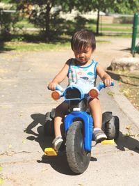 Cute boy riding motorcycle sitting on road