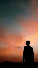 Silhouette man standing against orange sky