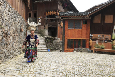 Full length portrait of woman standing outside house