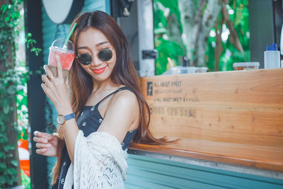 Young woman holding drink standing outdoors