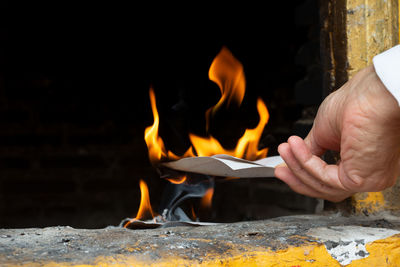 Cropped hand of man burning paper