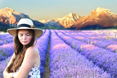 Portrait of beautiful young woman with pink flowers against sky