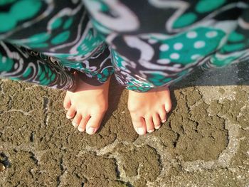 Low section of woman standing on sand