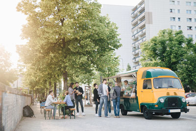 Male and female customers standing by food truck