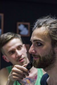 Young man getting make-up done by his friend