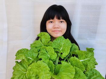 Portrait of smile girl holding chinese cabbage standing on white background