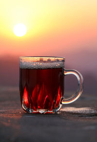 Close-up of tea in glass on table against sunset