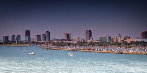 City skyline by sea against clear sky