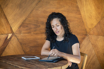 Woman using a digital tablet while sitting at a table.