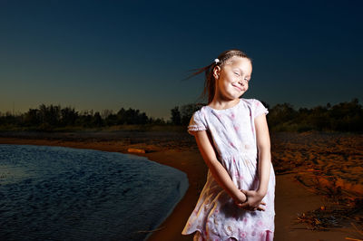 Smiling girl standing at beach against sky at night