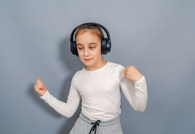 Dancing little girl in headphones listening to music. white t-shirt, gray sweatpants.