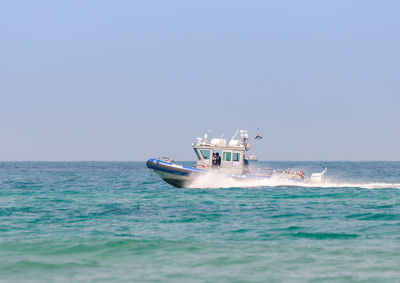 Boat sailing in sea against clear sky