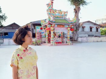 Girl looking away while standing against temple