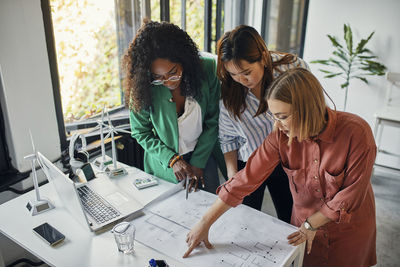 Businesswomen having a meeting in office with wind turbine models on table